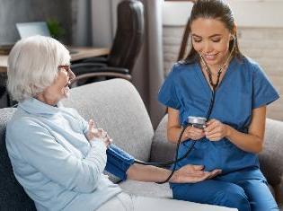 certified nursing assistant taking blood pressure on older woman